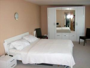 Un dormitorio con una cama blanca y un espejo. en Ferienhaus DH-38879, en Lubmin