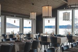 a dining room with tables and chairs and windows at Hotell Klimpfjäll in Klimpfjäll