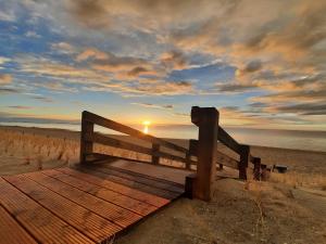 a wooden bench on the beach with the sunset at Ferienunterkünfte an der Düne DH-42986 in Lubmin