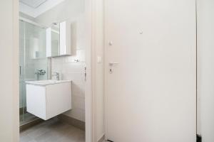 uma casa de banho branca com um lavatório e um espelho em GK Plato Academy em Atenas