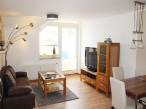 sala de estar con sofá, TV y mesa en Blaumuschel Haus A Wohnung 19 - DH, en Lubmin