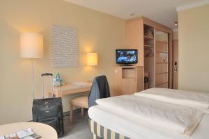 a room with two beds and a desk and a television at relexa Hotel Ratingen City in Ratingen