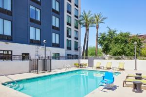 a swimming pool with chairs and a building at SpringHill Suites Phoenix Downtown in Phoenix