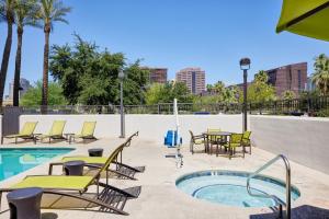 un patio con mesas y sillas junto a una piscina en SpringHill Suites Phoenix Downtown, en Phoenix