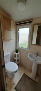 a bathroom with a toilet and a sink and a window at Brilliant 6 Berth Caravan At Dovercourt Holiday Park Ref 44009a in Great Oakley