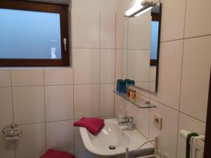 a white bathroom with a sink and a mirror at Haus Am Waldpark in Sankt Georgen im Schwarzwald