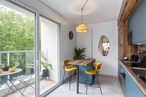 une cuisine avec une table et des chaises à côté d'une fenêtre dans l'établissement L'Air - Elégant 2 chambres avec loggia dans résidence de haut standing, à Rennes