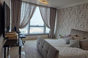 a bedroom with a couch and a large window at Reem Island 2BHK LUXURY APARTMENT! in Abu Dhabi