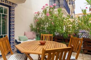 a wooden table and chairs on a patio with flowers at Apartamento Tocano Beach - By Dalma Portuguesa in Albufeira