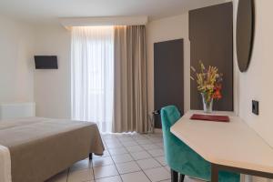 a hotel room with a bed and a table with flowers on it at Hotel Lo Smeraldo in Cisternino