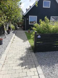 a brick walkway in front of a black house at Hunetorpvej Holiday Apartment in Blokhus
