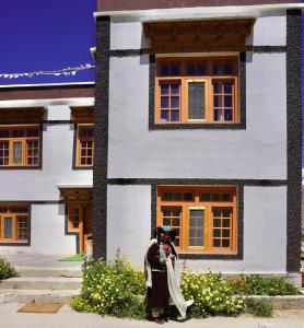 a woman standing in front of a white house at Guru view Home stay in Padam