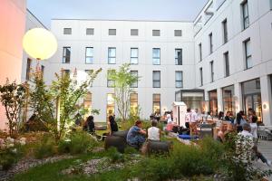 un groupe de personnes assises dans un jardin devant un bâtiment dans l'établissement The Ruck Hotel, à Lyon