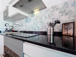 a kitchen with a black counter top with tropical wallpaper at La Isla , tu hogar en Torre del Mar. in Torre del Mar