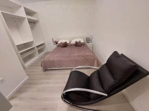 a bedroom with a bed and a black chair at Holiday Home Tesla - Novouređen s terasom in Šibenik