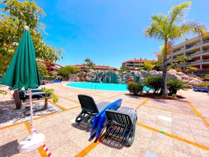 een zwembad in het resort met stoelen en een parasol bij Tropicalidays Jardines del Teide in Puerto de la Cruz