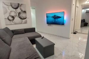 sala de estar con sofá y TV en la pared en Holiday Home Tesla - Novouređen s terasom, en Šibenik
