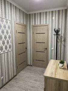 a hallway with two wooden doors and a table at ЖК Нектар in Aktobe