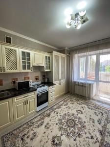 una cocina con armarios blancos y una alfombra grande en ЖК Нектар, en Aktobe