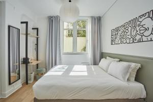Un dormitorio con una gran cama blanca y una ventana en Hôtel Beauquartier Montmartre en París