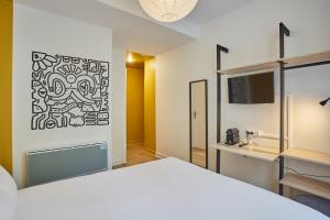 Un dormitorio con una cama blanca y un lavabo. en Hôtel Beauquartier Montmartre, en París