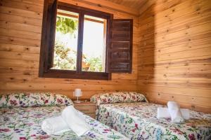 two beds in a log cabin with a window at Complejo Rural La Tejera in Elche de la Sierra