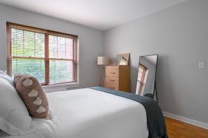 a white bedroom with a bed and a mirror at Evanston 1br w courtyard wd nr beach CHI-955 in Evanston