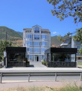 a large white building with black balconies next to a street at Pashkaj Hotel in Pogradec