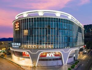 Guangzhou Wogo Yuanbao Hotel - Zhujiang New Town في قوانغتشو: مبنى به الكثير من النوافذ على شارع المدينة