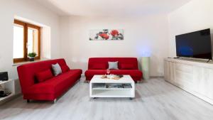 a living room with two red chairs and a tv at Casa di Elena in Iglesias