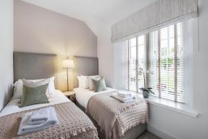 two beds in a room with a window at The Woodside Apartments in Doune