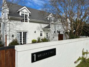 Un cartello su un muro bianco di fronte a una casa di Courtyard on Weder a Greyton