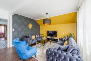 Elle comprend un salon doté d'un mobilier bleu et d'un mur jaune. dans l'établissement L'Adeline - Charmant appartement, à Lingolsheim