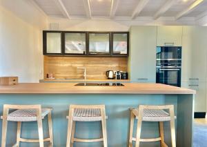 a kitchen with two stools at a counter with a sink at La Villa du Lac - piscine chauffée - Jacuzzi - clim in La Teste-de-Buch
