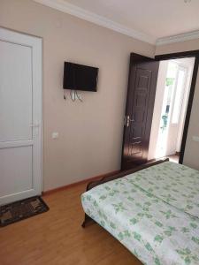 a bedroom with a bed and a television on the wall at Guest House GioRgi in Kobuleti