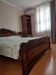 a bedroom with a bed with a wooden frame and a window at Guest House GioRgi in Kobuleti