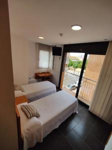 a hotel room with two beds and a balcony at Hostal Manel in Pineda de Mar