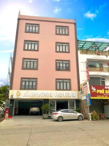 un edificio rosa con un coche aparcado delante de él en Bình Long II Hotel, en Lai Châu