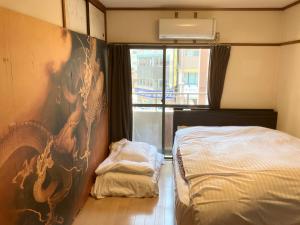 ein Schlafzimmer mit einem Bett und einem Wandgemälde in der Unterkunft Casa Viento Stay Inn in Hiroshima