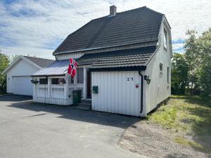 a white building with a black roof and a flag at Oslo Guest House Twin & Family room in Kjeller