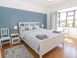 a bedroom with a white bed and a blue wall at Awelfryn in Holyhead