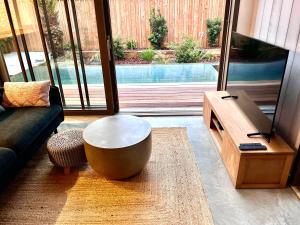 a living room with a couch and a table and a tv at La Villa du Lac - piscine chauffée - Jacuzzi - clim in La Teste-de-Buch