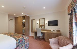 a hotel room with a bed and a desk and a television at Arundel House Hotel in Cambridge