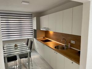a kitchen with white cabinets and a sink and a table at ANET Apartman Visoko in Visoko