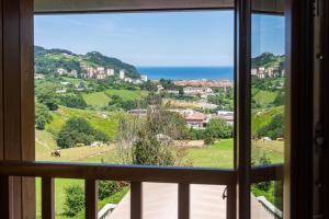 a window with a view of a town and the ocean at Agroturismo Argoin Txiki in Zarautz