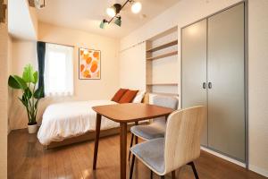 Schlafzimmer mit einem Bett, einem Tisch und Stühlen in der Unterkunft WINBELL DUET Ebisu5 in Tokio