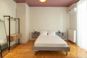 a bedroom with a bed with white sheets and a mirror at Casanova94 Guesthouse in Piraeus
