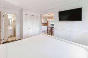 a white bedroom with a flat screen tv on a wall at Travelodge by Wyndham Traverse City MI in Traverse City