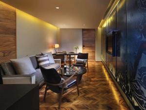 a living room with a couch and a table and chairs at SO/ Bangkok in Bangkok