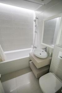 a white bathroom with a sink and a toilet at Luxuriously flat fully equipped quality appliances in Tulcea +12 photos